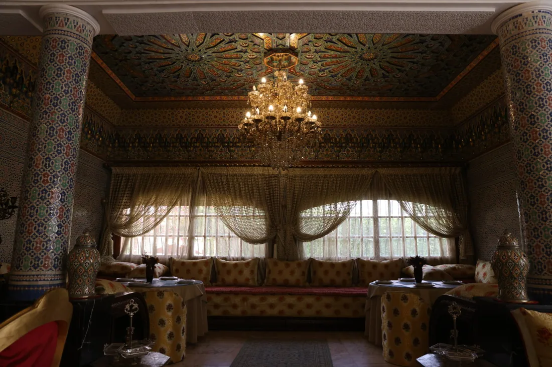 The grand salon: painted cedar ceiling, chandelier, zellige columns and draped arches.